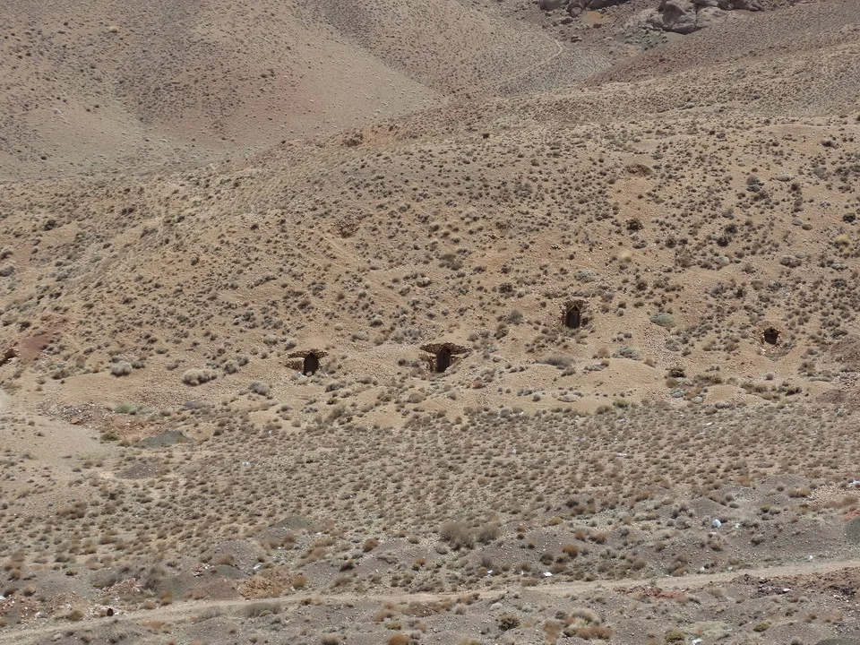 Paesaggio arido e collinare in Iran con terreno bruno e basso vegetazione.