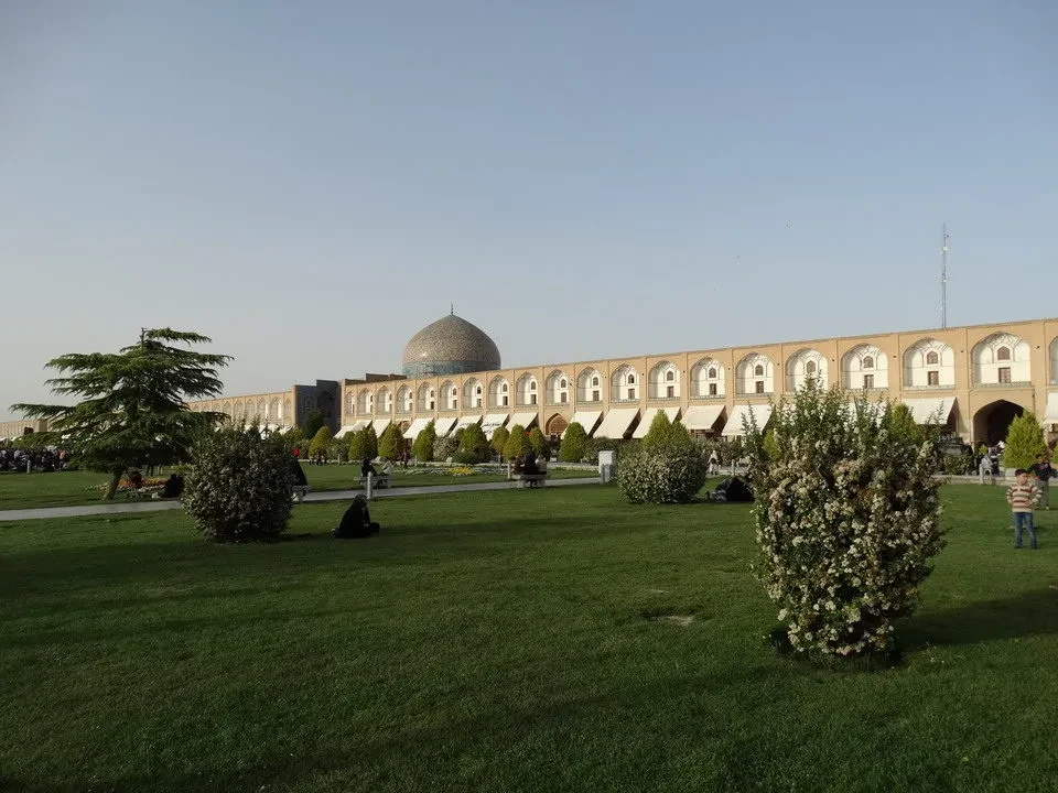 Una veduta ampia della piazza Imam a Isfahan in Iran con edifici storici e un grande spazio verde in primo piano.