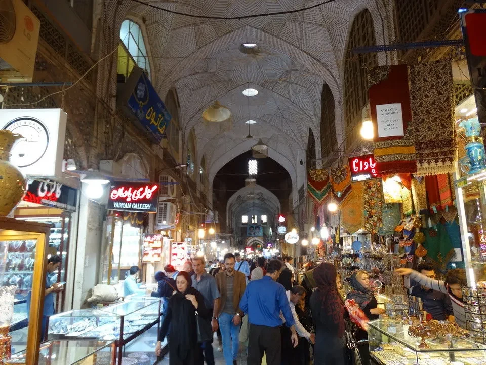 Una veduta interna di un mercato tradizionale in una città iraniana con negozi affollati.