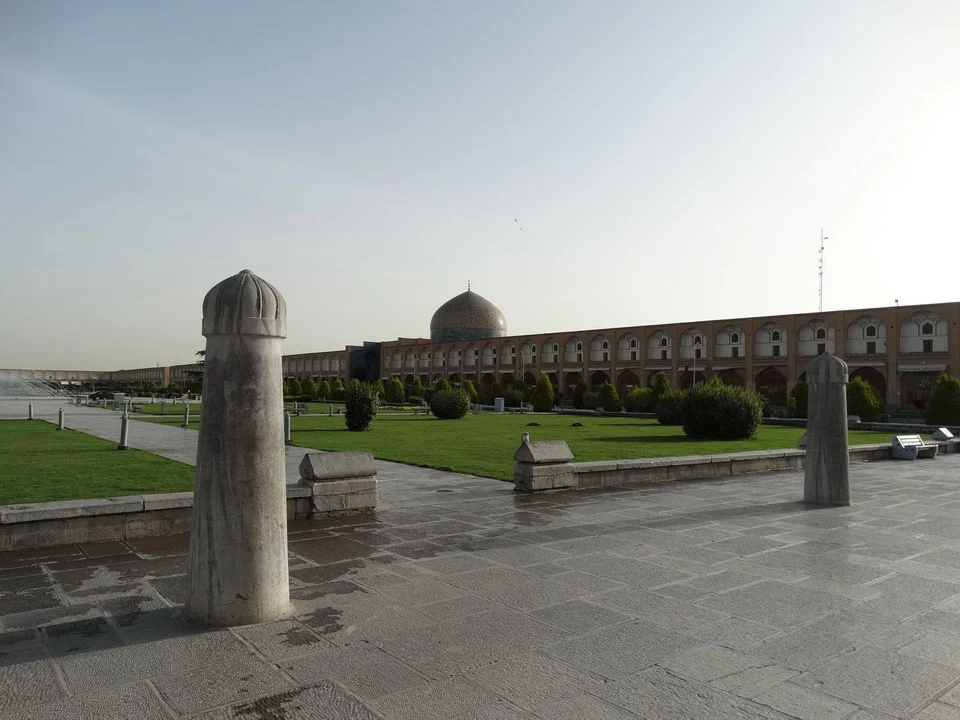 Una veduta ampia della piazza Imam a Isfahan in Iran con edifici storici e elementi architettonici in primo piano.