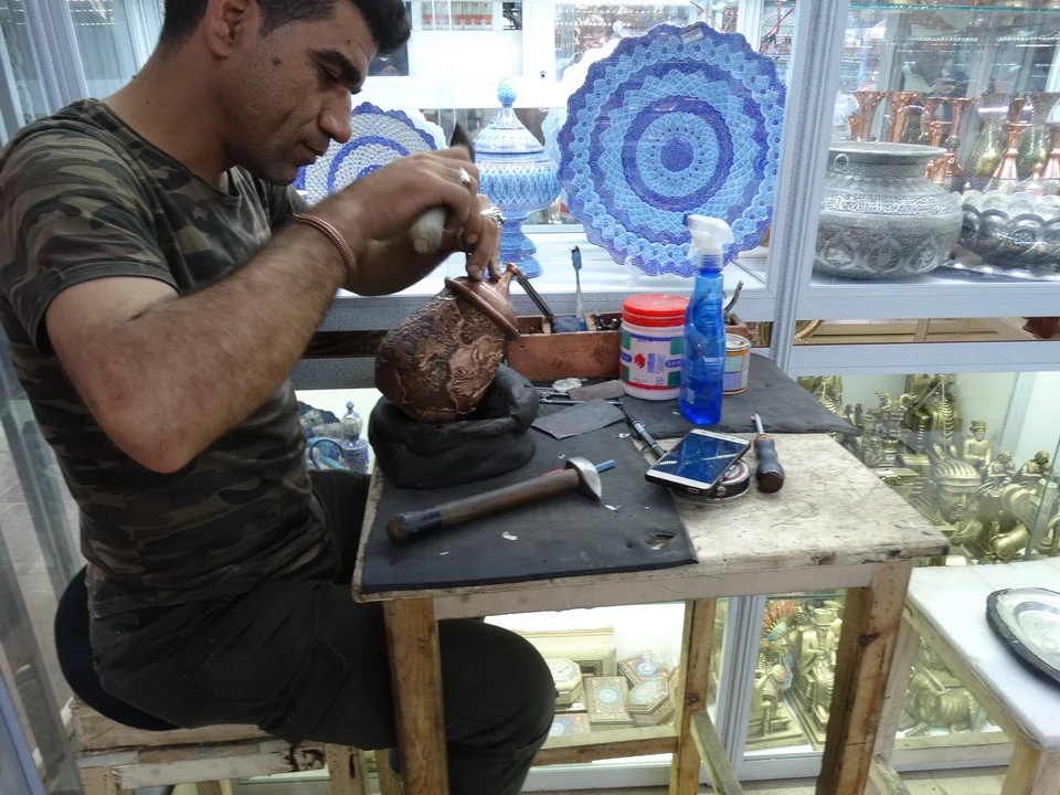 Un artigiano lavora la ceramica su un tavolo in Iran.