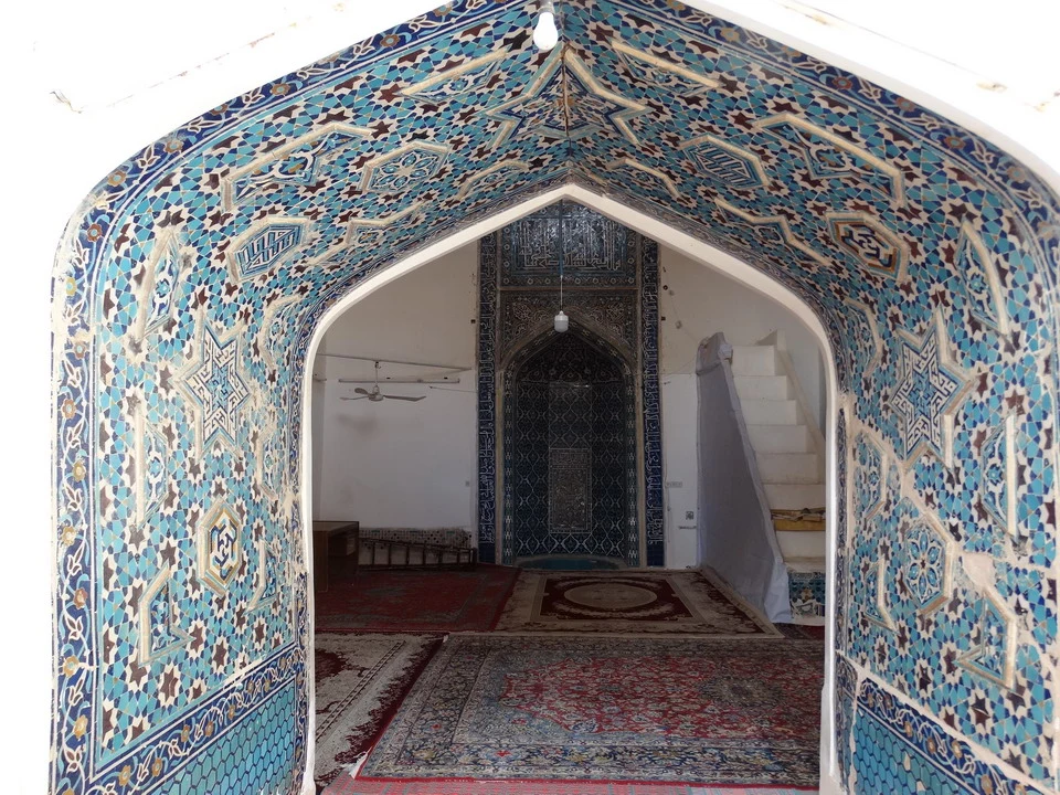 Interno di una moschea decorata con intarsi intricati e soffitti a volta riccamente decorati.