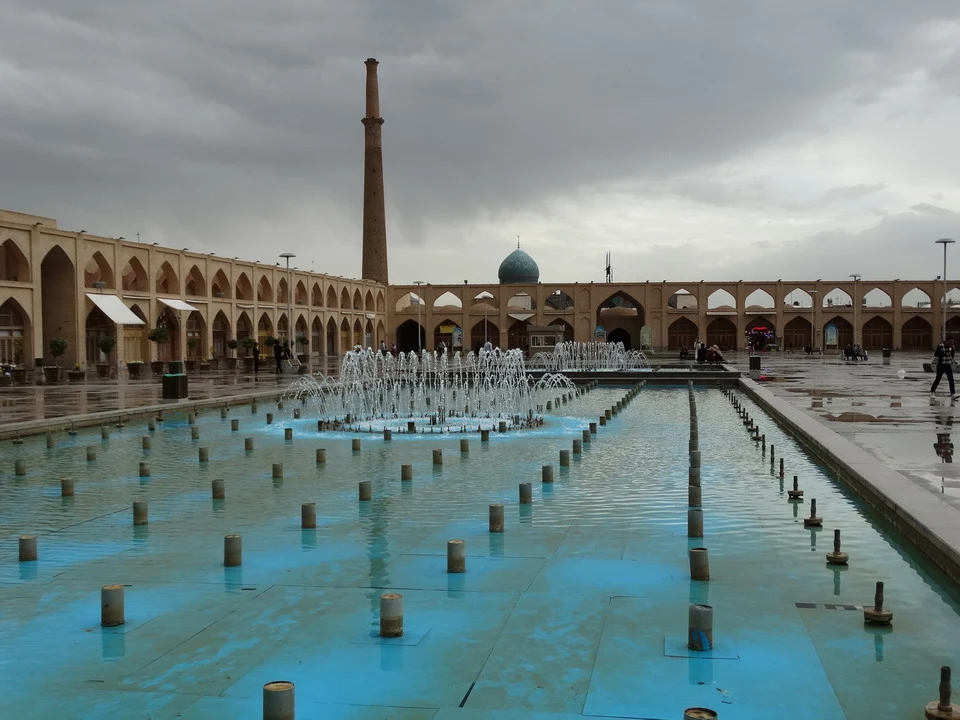 Vasca con fontane nella piazza Imam Ali di Esfahan sotto un cielo temporalesco.