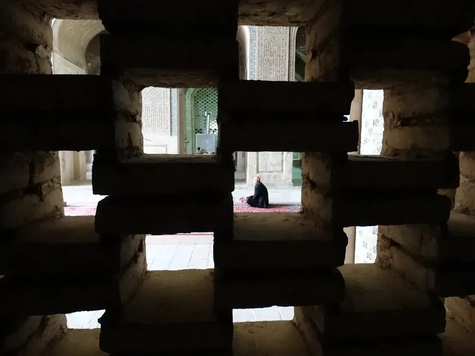 Interno di un edificio antico con archi in pietra e luce che filtra dalle aperture.