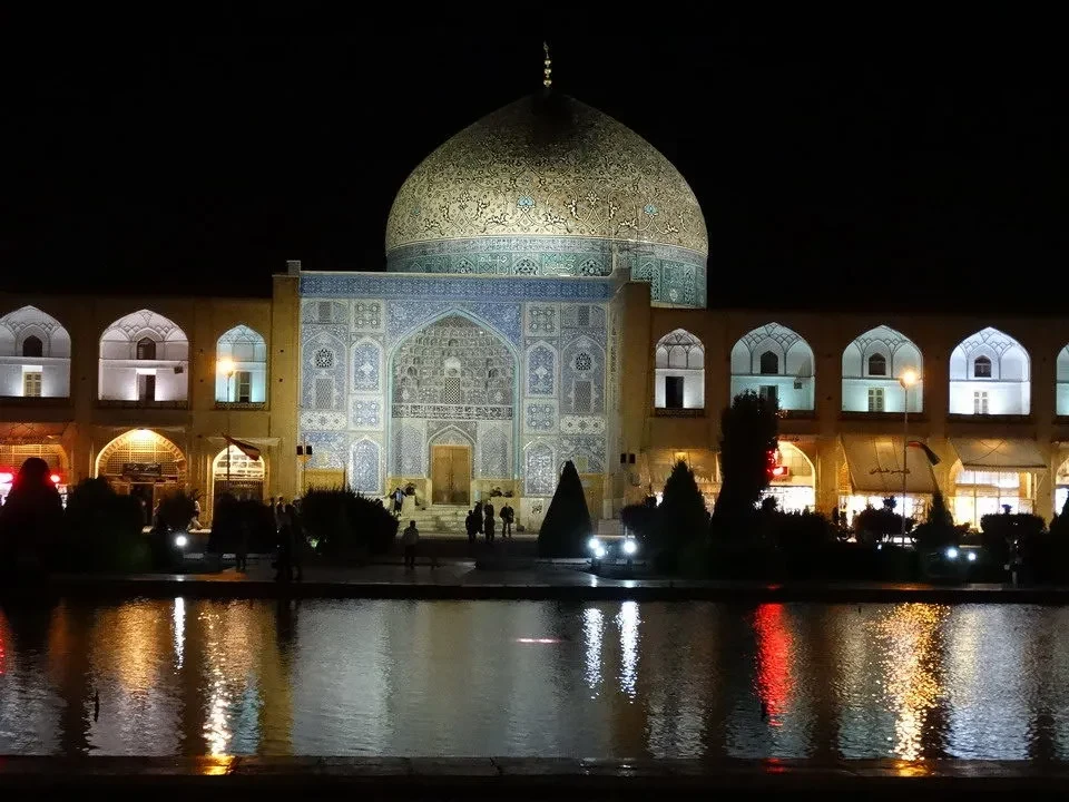 Piazza Imam illuminata di notte con architetture tradizionali iraniane.
