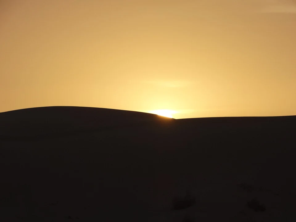 Silhouette delle dune di sabbia all'alba su un paesaggio arido in Iran.
