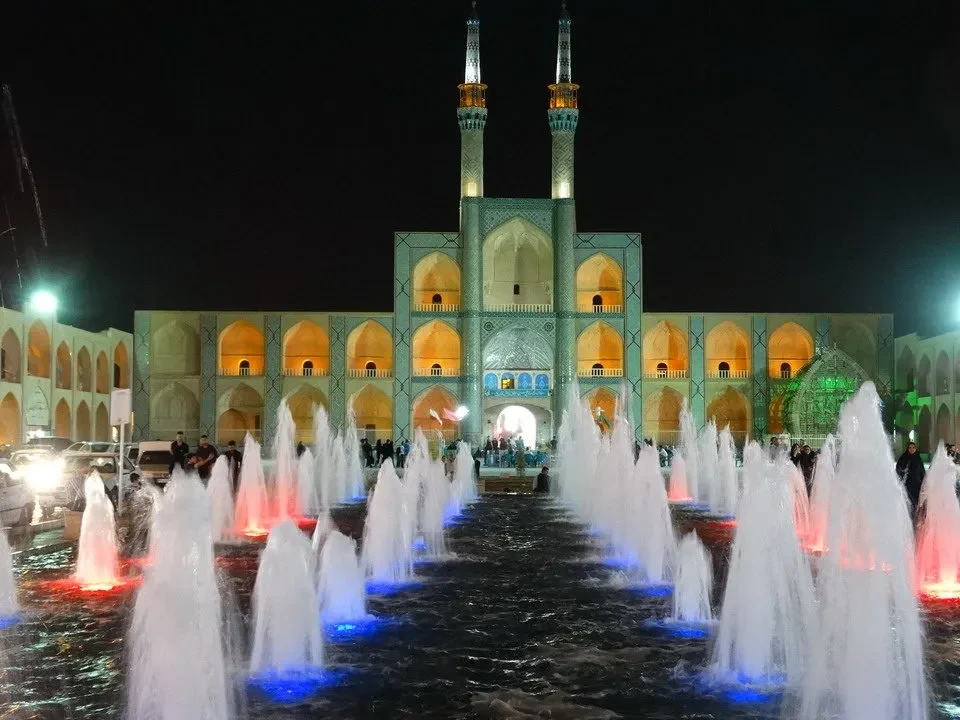 Una fontana illuminata in un complesso architettonico iraniano di notte.