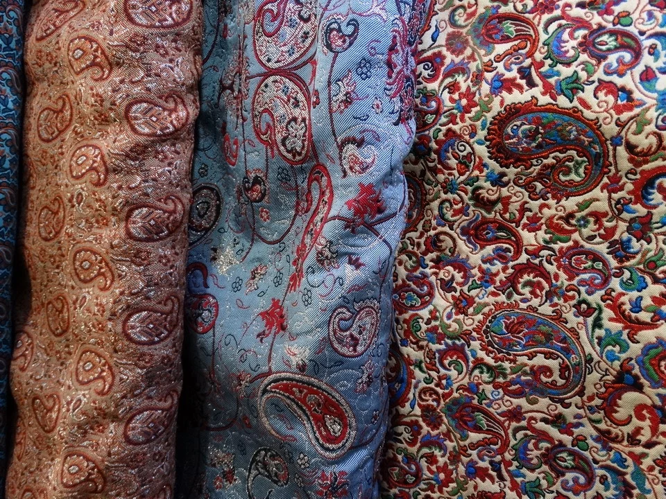 Tessuti riccamente decorati in vari colori e motivi sono esposti in una galleria fotografica.
