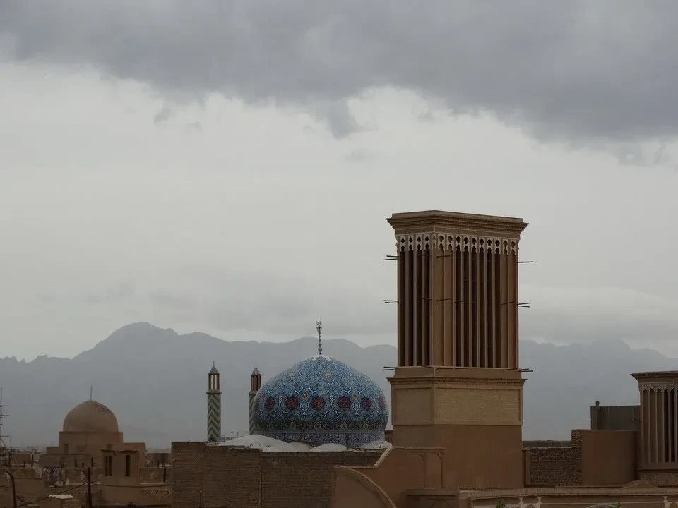Paesaggio urbano di Yazd con cupole e torri sotto un cielo coperto.
