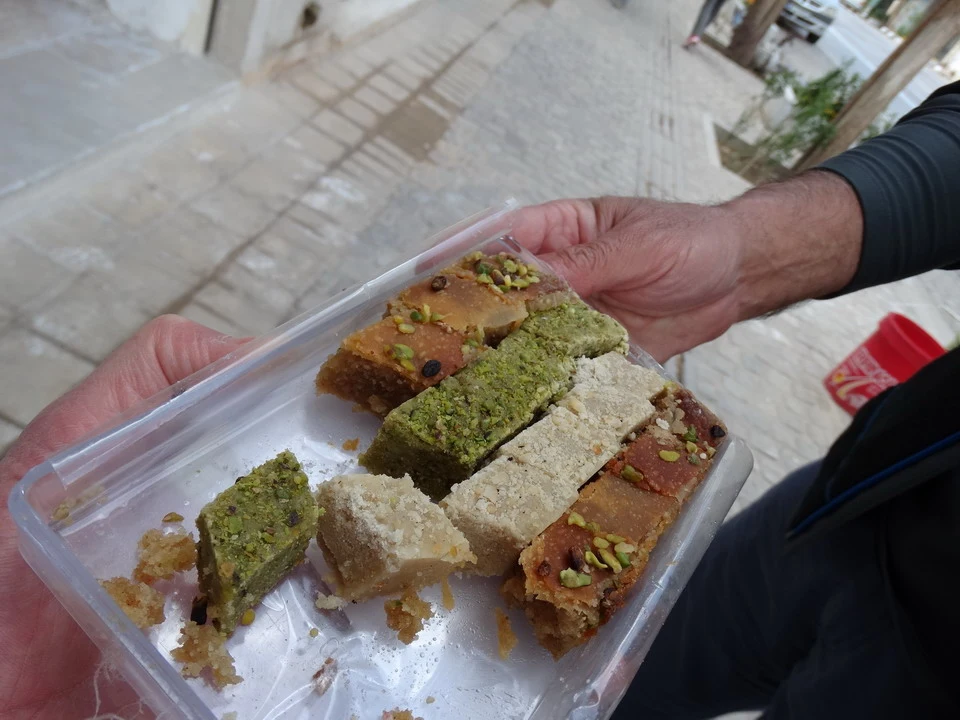 Un piatto di baklava viene tenuto da una mano in primo piano.