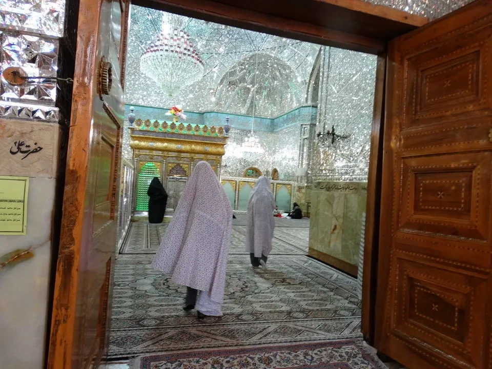 Interni di un edificio storico in Iran con persone che passeggiano in un corridoio decorato.