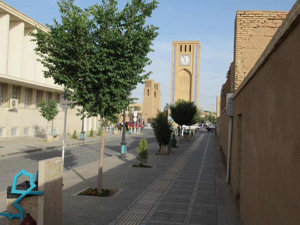 Una torre dell'orologio in mattoni si erge lungo una strada in Iran.