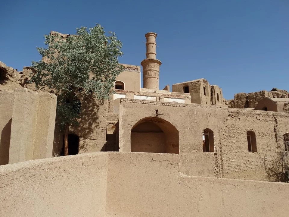 Vista di un edificio in argilla con una torre e alberi in Iran.