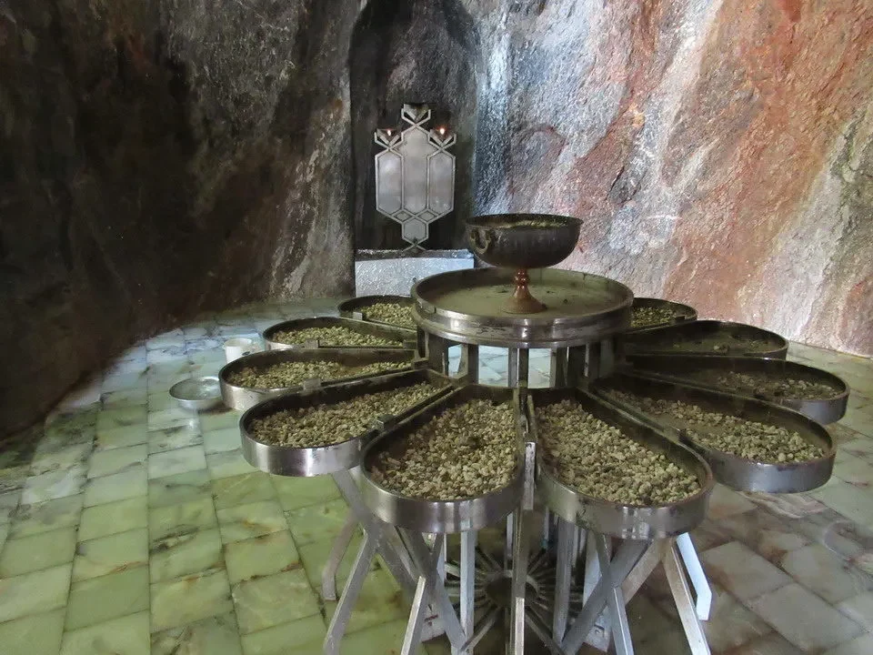 Disposizione di contenitori metallici su una base in pietra all'interno di una grotta o ambiente rupestre.