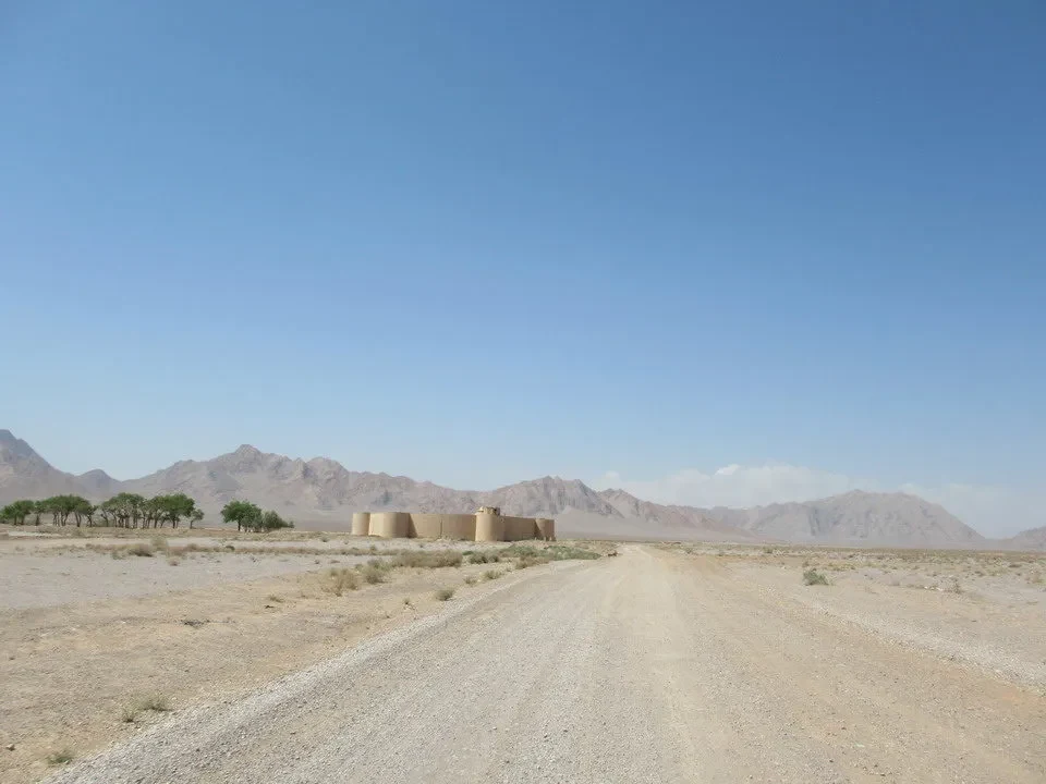 Un caravanserraglio in pietra si trova su una strada sterrata nel deserto iraniano.