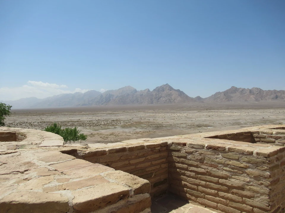 Resti di mattoni antichi che fronteggiano un paesaggio desertico montuoso in Iran.