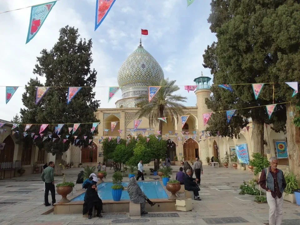 Vista esterna di un complesso religioso in Iran con cupole e cortili alberati.