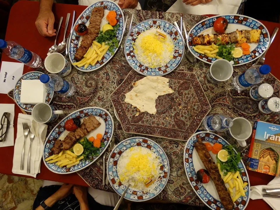 Una tavola apparecchiata con diversi piatti di cibo in un contesto serale in Iran.