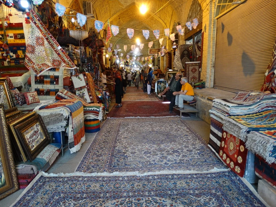 Interno di un bazar iraniano pieno di tappeti e tessuti colorati.