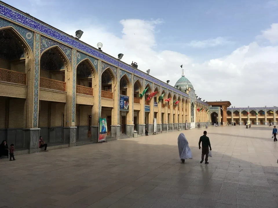 Una vista ampia dell'architettura tradizionale iraniana con archi decorati e una grande piazza antistante.