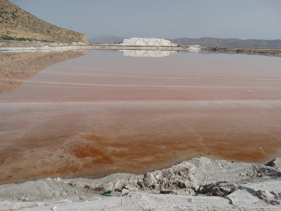 Un lago rosa riflette il paesaggio arido dell'Iran.