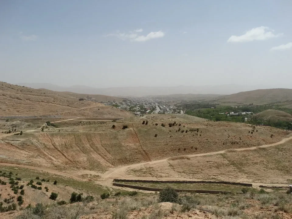 Paesaggio collinare secco in Iran con una strada che attraversa il terreno.