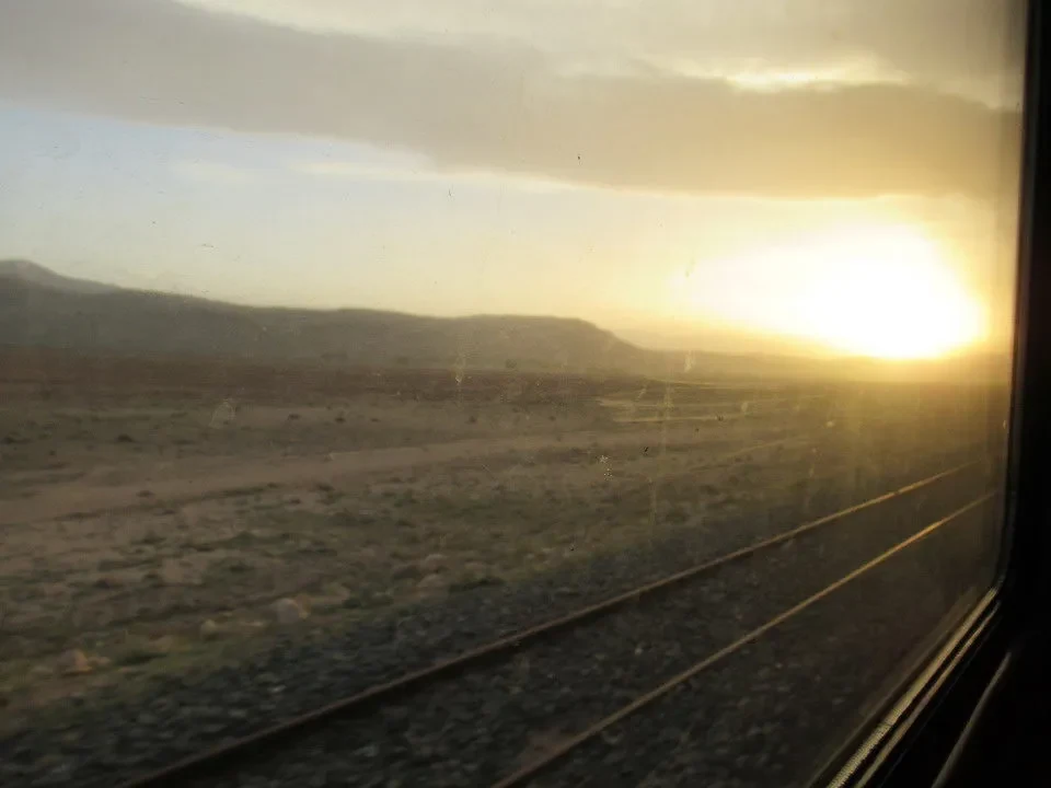 Un treno viaggia attraverso un paesaggio arido all'alba in Iran.