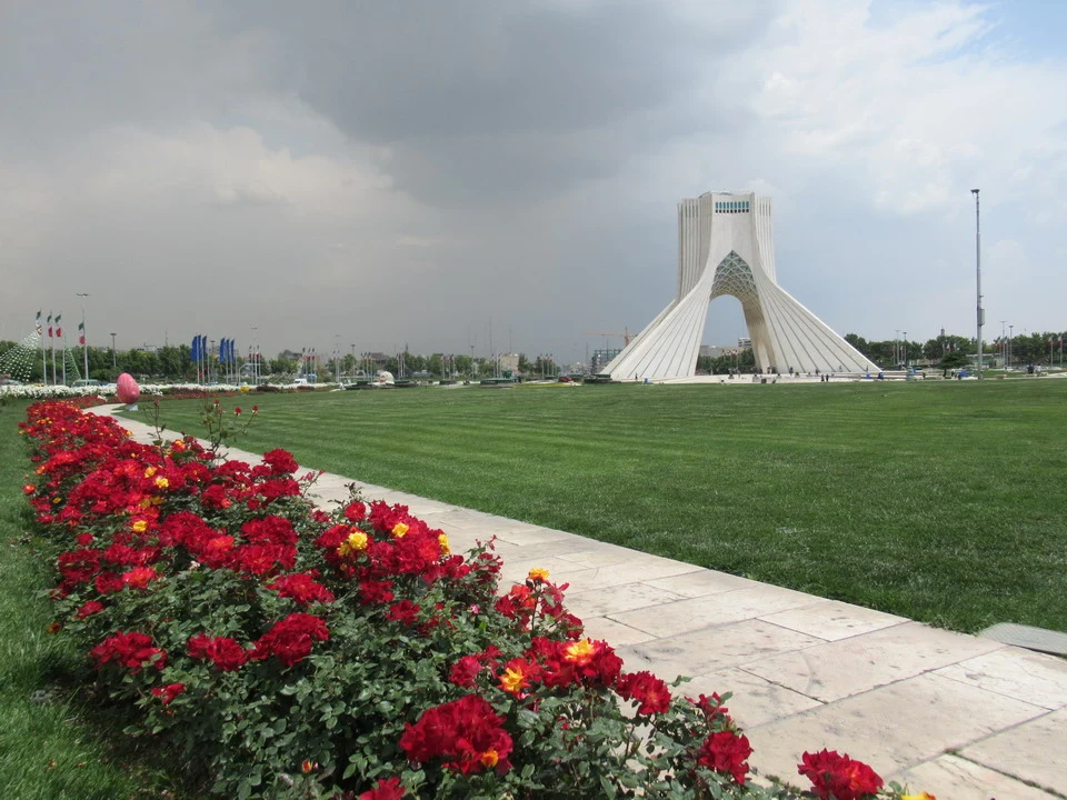 La Torre Azadi è visibile in un ampio spazio verde con fiori in primo piano.