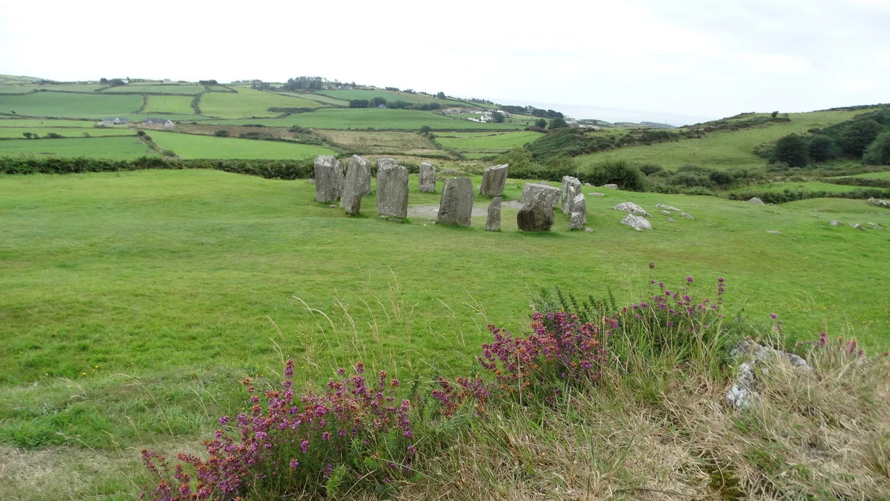 Un cerchio di pietre erette si estende attraverso un paesaggio verde in Irlanda.