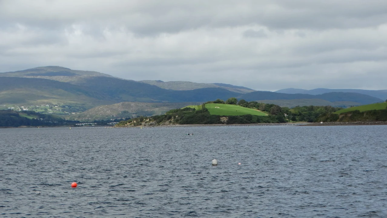 Paesaggio marino con isole verdi e colline sotto un cielo nuvoloso in Irlanda.