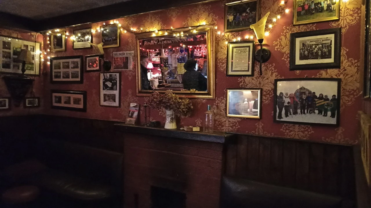 Interno caldo e decorato di un pub irlandese con molte fotografie incorniciate.