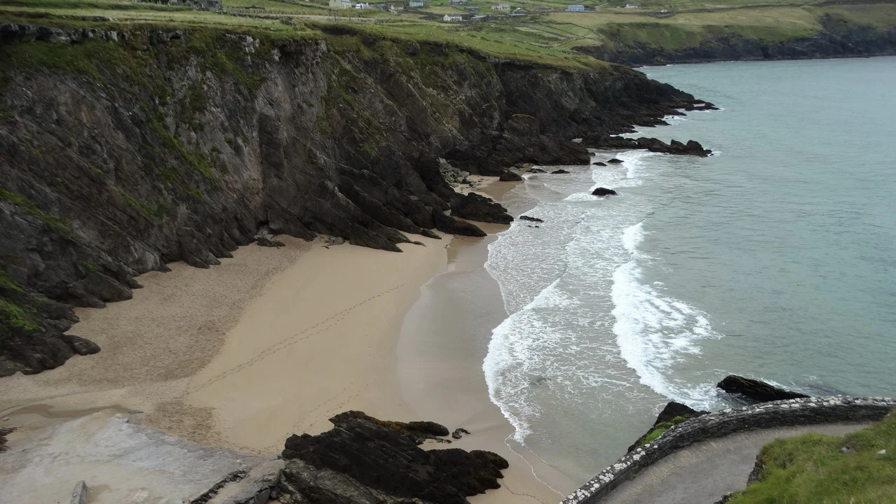 Una scogliera rocciosa costeggia una spiaggia sabbiosa lungo la costa irlandese.