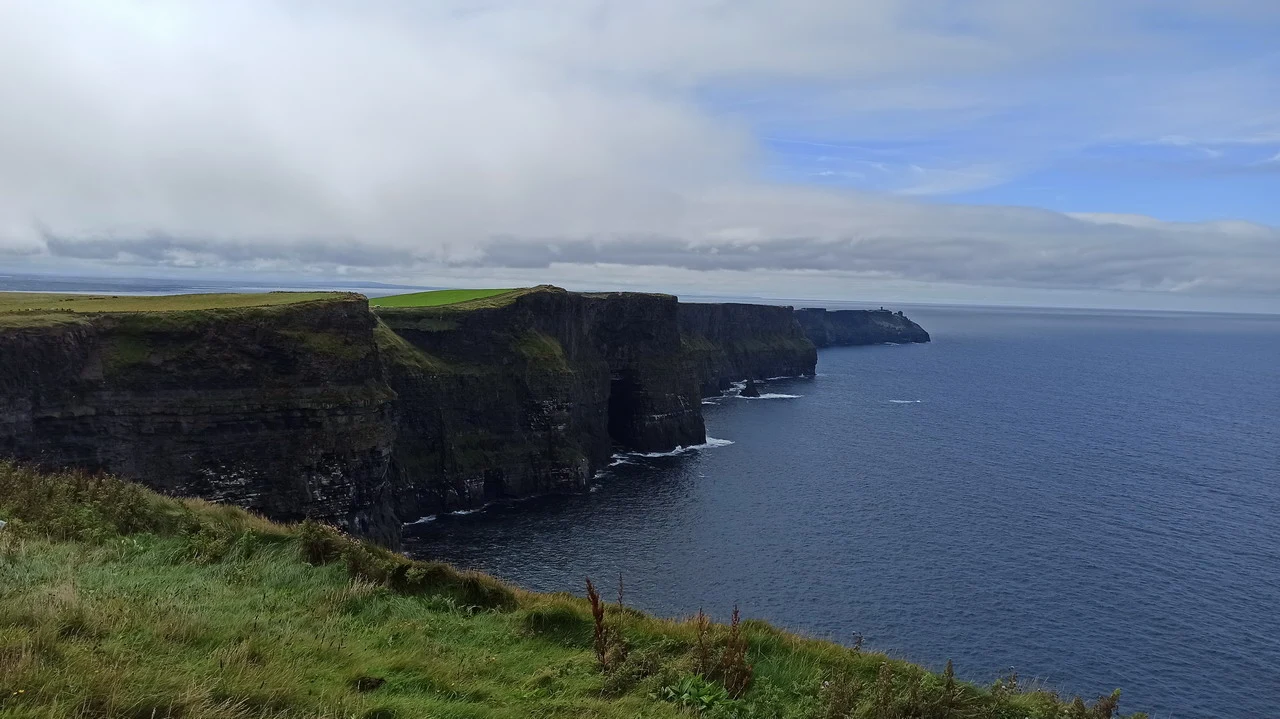 Le scogliere di Moher in Irlanda si estendono lungo la costa oceanica sotto un cielo nuvoloso.