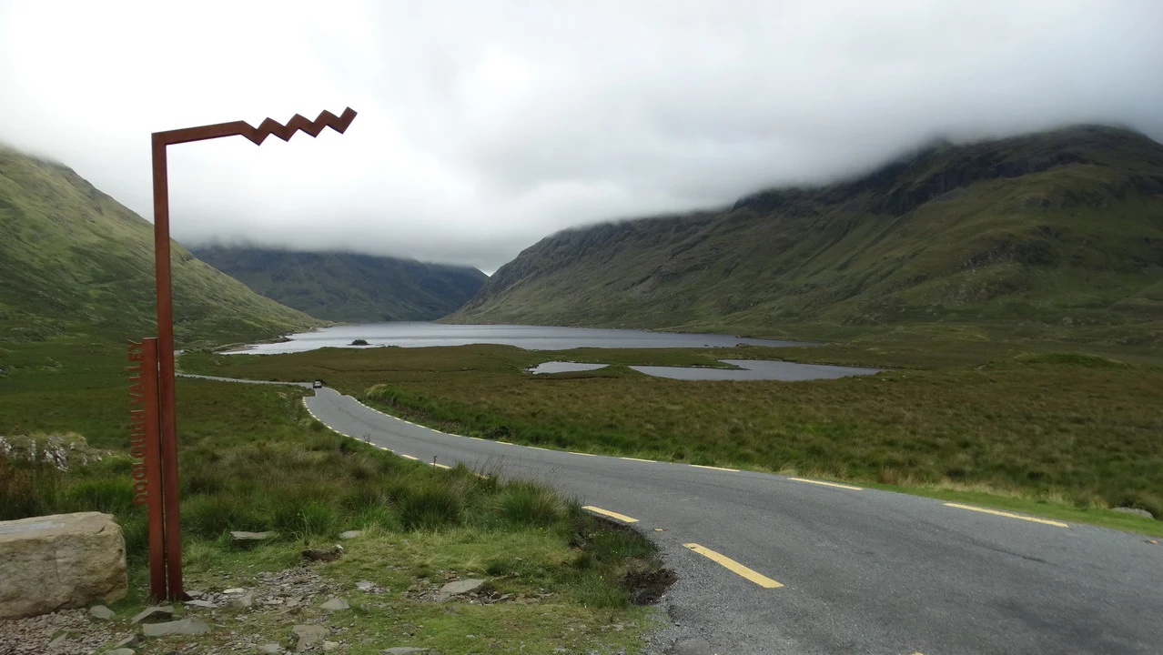 Una strada serpeggia attraverso un paesaggio montano irlandese coperto di nebbia.