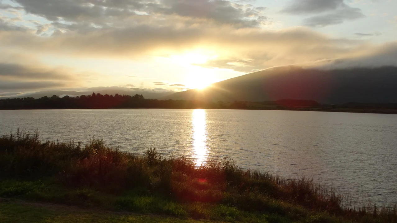 Riflesso del sole sull'acqua di un lago irlandese al tramonto.