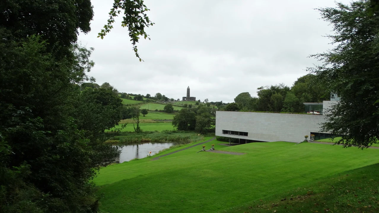 Vista panoramica di un edificio moderno immerso nel verde irlandese con una torre in lontananza.