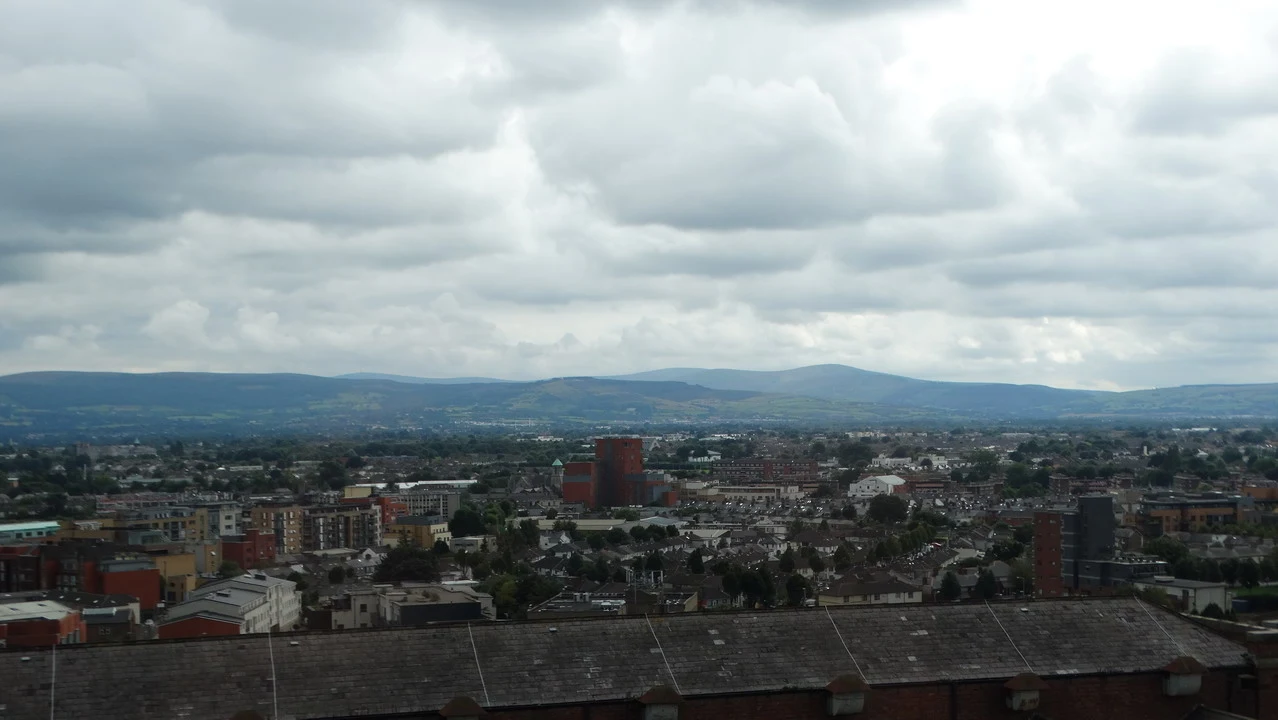Vista panoramica di Dublino con il Guinness Storehouse visibile in lontananza sotto un cielo nuvoloso.