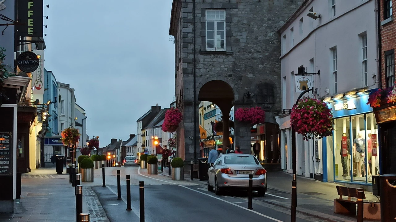 Una strada acciottolata in una città irlandese al tramonto con edifici storici e decorazioni floreali.