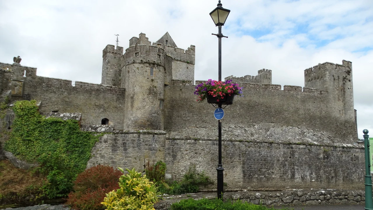 Mura di pietra di un castello in Irlanda con vegetazione ai lati.