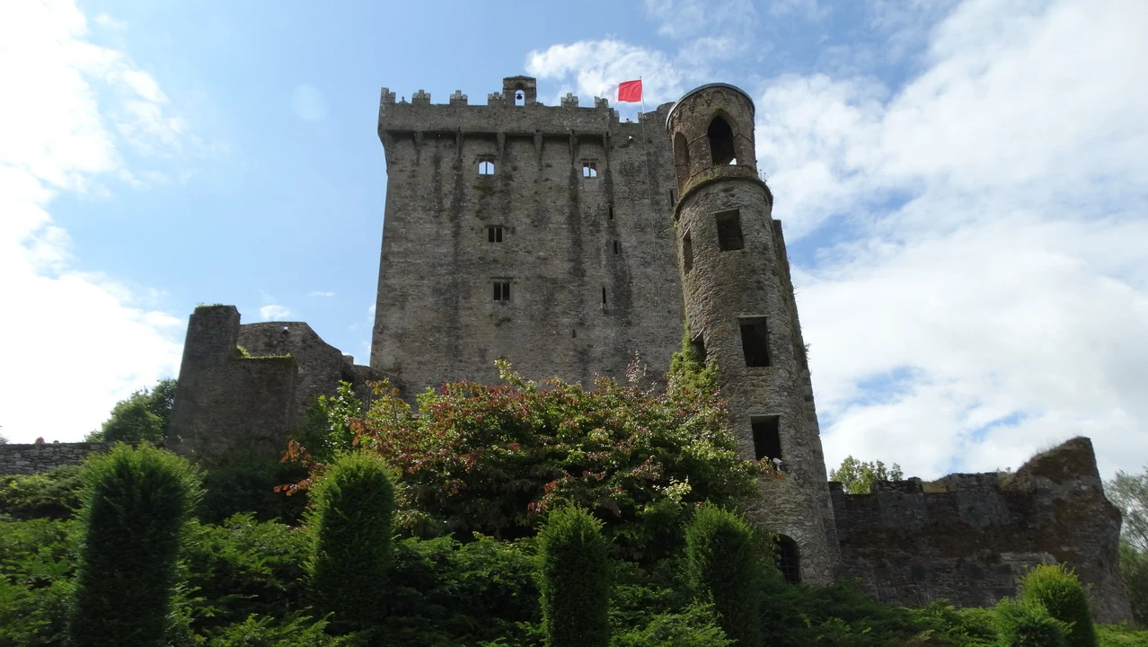 Castello di Blarney in Irlanda con mura imponenti e vegetazione circostante.