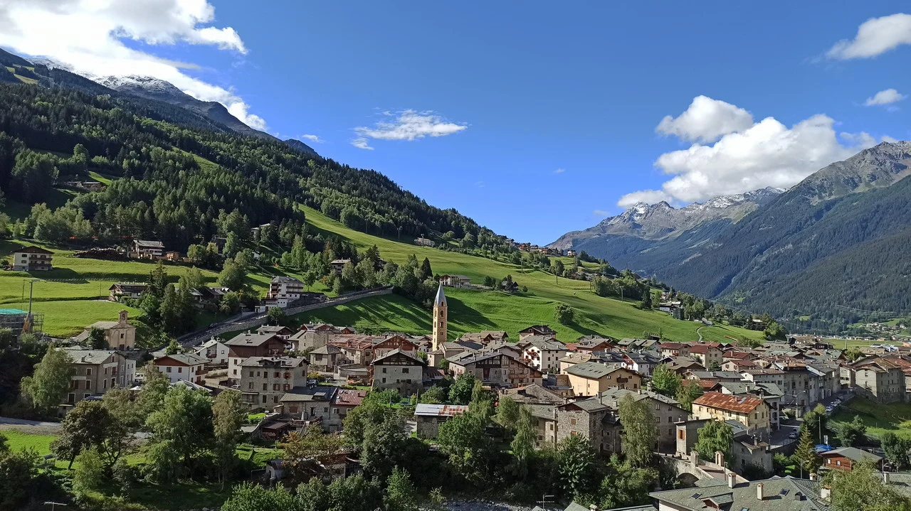 Cavalieri attraversano le Alpi italiane in un paesaggio montano.