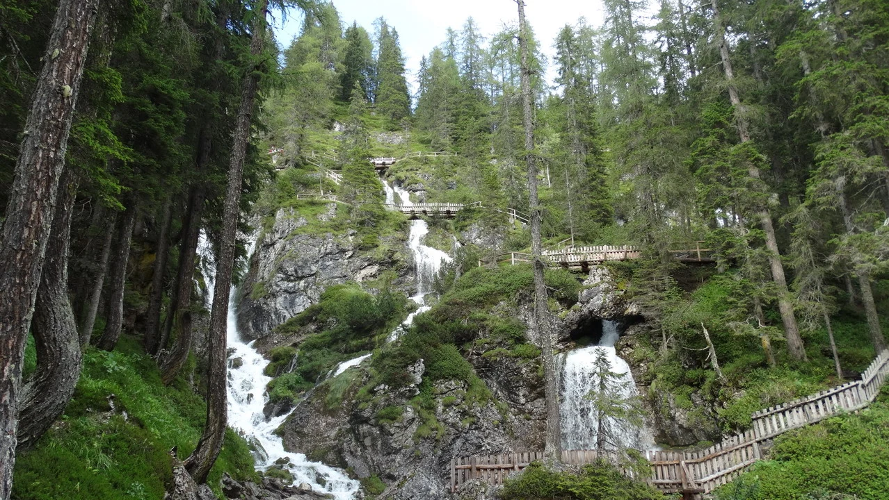 Cavalieri attraversano una cascata nella valle alpina italiana.