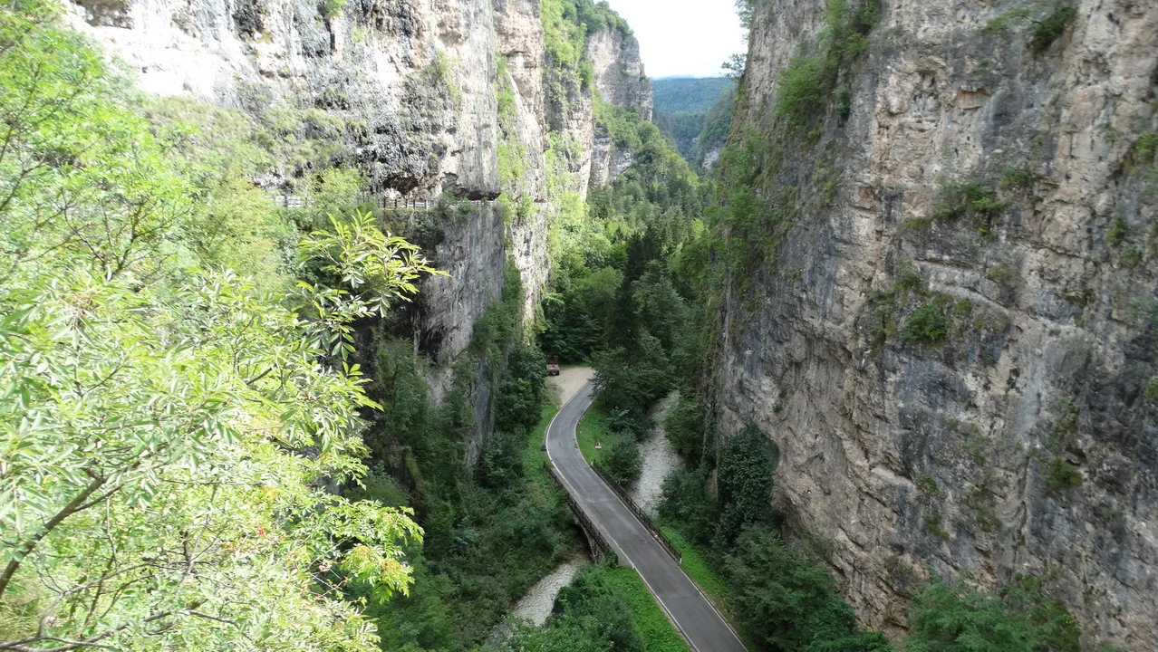 Cavalieri percorrono un sentiero stretto tra le pareti rocciose delle Alpi italiane.