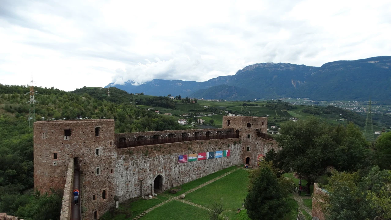Cavalieri attraversano un paesaggio montano con un castello in pietra sullo sfondo.