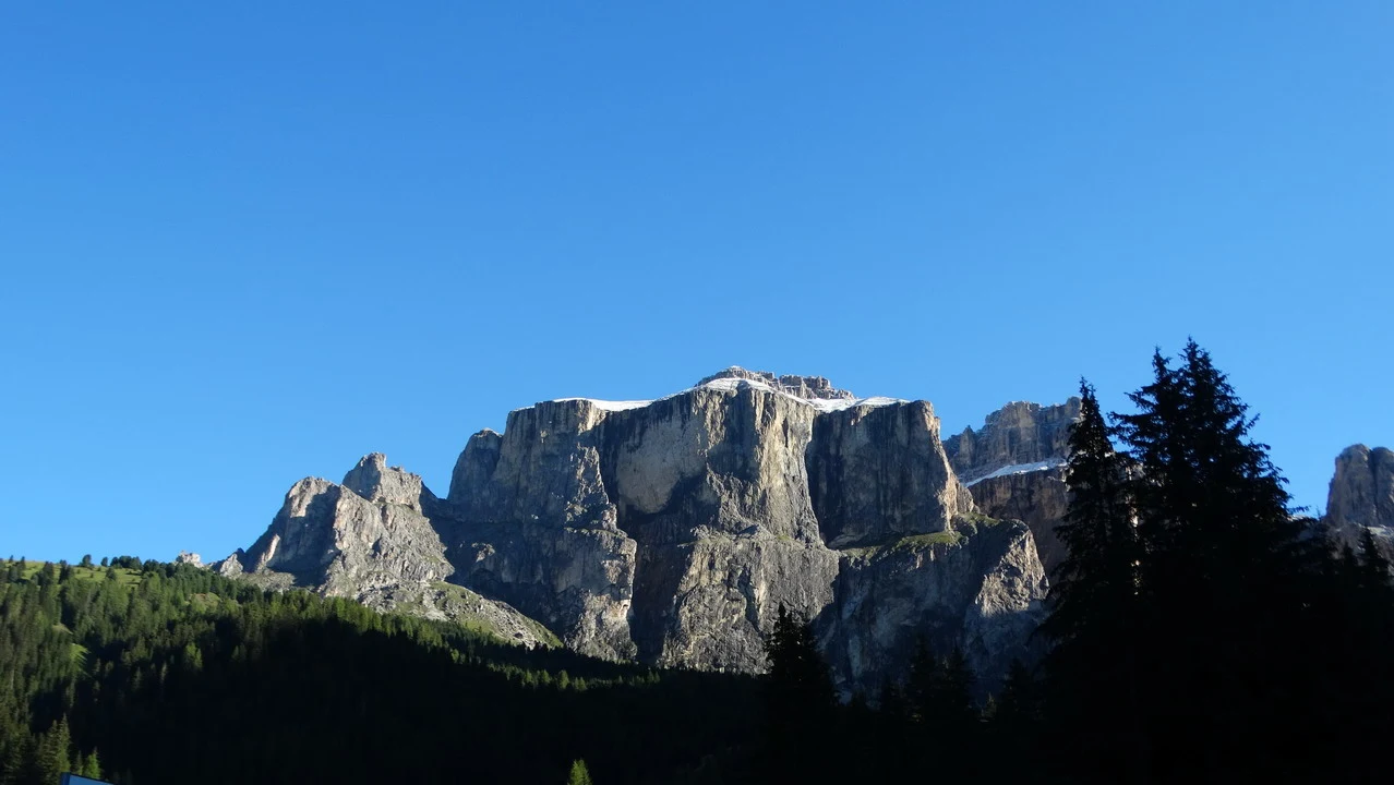 Paesaggio montano delle Alpi con cime rocciose e foreste innevate.
