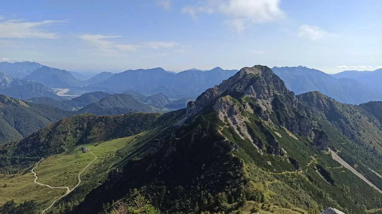 Cavalieri attraversano le montagne delle Alpi italiane in una vasta veduta panoramica.