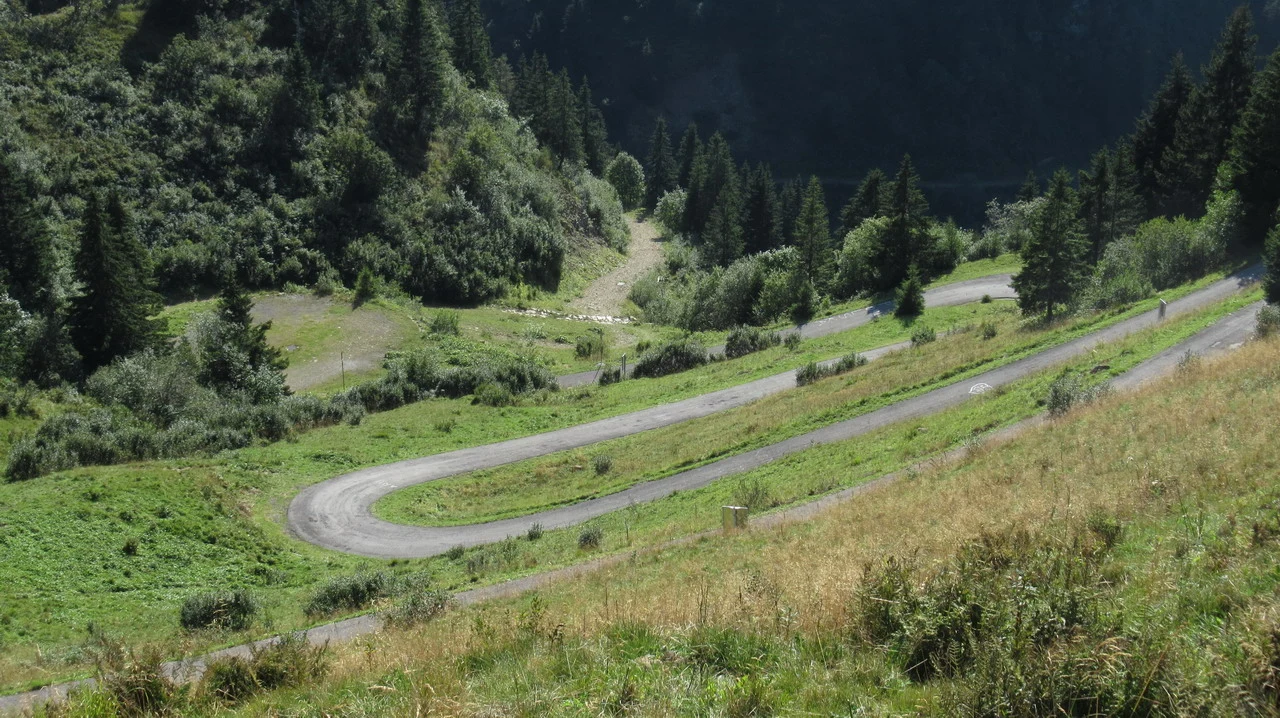 Una strada sinuosa attraversa un paesaggio montano verdeggiante durante una corsa in moto.
