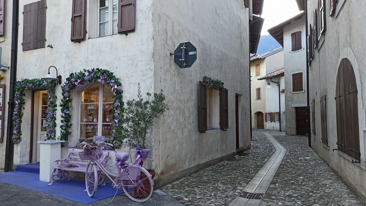 Una pittoresca via lastricata in un borgo delle Alpi italiane con edifici storici.