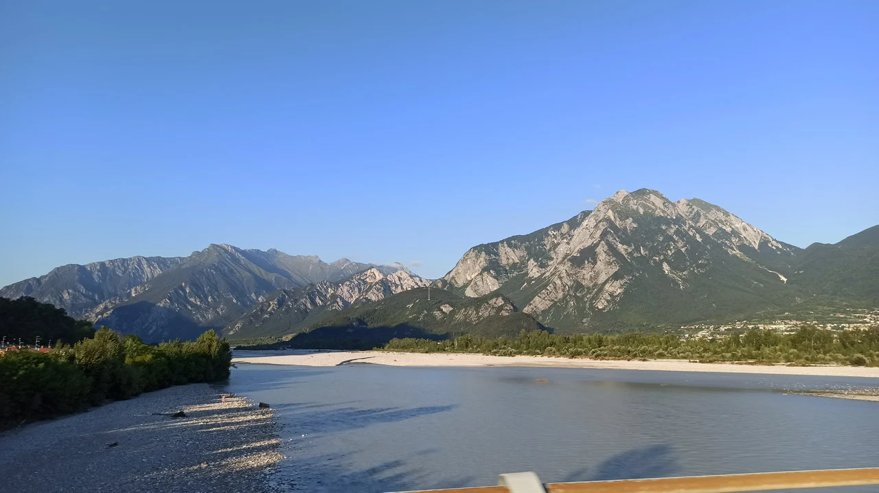Cavalieri attraversano un fiume ai piedi delle Alpi italiane.