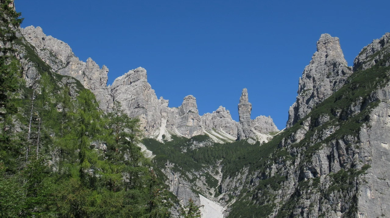 Cavalieri attraversano le vette delle Alpi italiane con uno sfondo montuoso.